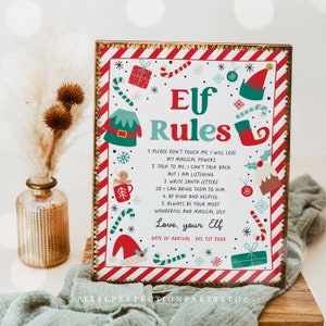 May include: A decorative sign with the words "Elf Rules" in a festive design. The sign has a red and white striped border with Christmas-themed illustrations. The text includes rules for interacting with an elf, with a gold-colored frame.