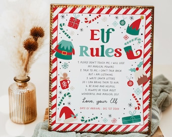 May include: A framed sign with a festive design featuring the text "Elf Rules." The sign has a red and white striped border with Christmas-themed illustrations like candy canes, elf hats, and presents. The text includes rules for interacting with an elf.