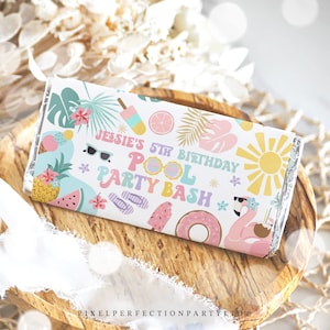May include: A white chocolate bar wrapper with a colorful tropical theme. The wrapper features a pink flamingo, a watermelon, a pineapple, a donut, and sunglasses. The text on the wrapper reads "Jessie's 5th Birthday Pool Party Bash".