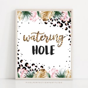 May include: A framed print with the words "watering hole" in a leopard print font and black font. The print is decorated with watercolor illustrations of pink flowers, green leaves, and gold leaves, with black leopard print spots.