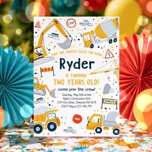 May include: A rectangular construction-themed birthday invitation card featuring yellow excavators, dump trucks, and cranes on a white background with black and yellow confetti. Text reads: Ryder is turning two years old! Come join the crew!
