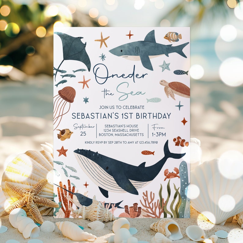 May include: A light blue and white invitation card with a whimsical under the sea theme. The card features a whale, a shark, a turtle, a jellyfish, and other sea creatures. The text on the card reads "Oneder the Sea" and "Sebastian's 1st Birthday".