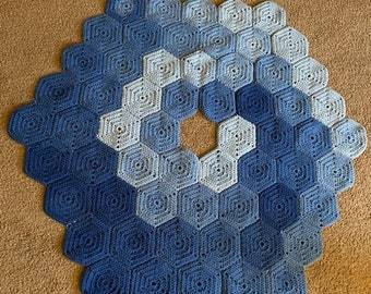 Può includere: Una coperta esagonale all'uncinetto blu e bianca con un motivo a spirale.