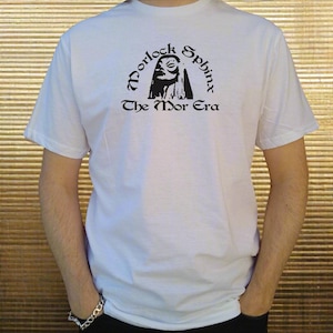 May include: White t-shirt with a black graphic print of a woman's face with the text "Morlock Sphinx The Mor Era".