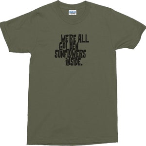 Puede incluir: Una camiseta verde con el texto "We're all golden sunflowers inside."
