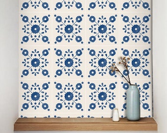 Könnte beinhalten: Eine Wand, die mit weißen Fliesen mit einem blauen Blumenmuster bedeckt ist. Die Fliesen sind in einem Gittermuster angeordnet. Eine kleine Vase mit getrockneten Blumen und ein weißer Salzstreuer stehen auf einem Holzregal vor der Wand.
