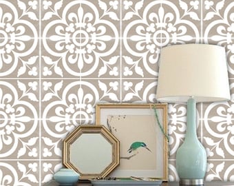 May include: A decorative wall with a repeating pattern of white floral designs on a tan background. A dark wooden table holds a gold framed mirror, a framed picture with a bird, a small blue vase, and a light blue lamp with a cream shade.