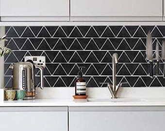 May include: A kitchen with white cabinets and a black triangle tile backsplash. A silver kettle and a bottle of soap are on the counter. A magnetic knife holder with several knives is mounted on the backsplash.