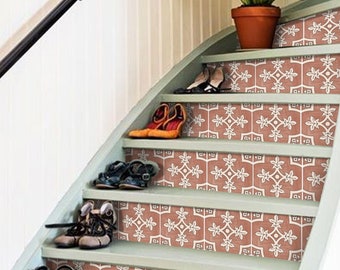 May include: A staircase with light green painted treads and risers decorated with a repeating white floral tile pattern. Several pairs of shoes are placed on the steps, and a green potted plant sits on the top landing near a black handrail.