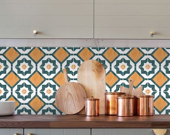 Puede incluir: Un salpicadero de cocina con un patrón geométrico de azulejos de color verde azulado, blanco y naranja. El salpicadero está sobre una encimera con tablas de cortar de madera y botes de cobre.