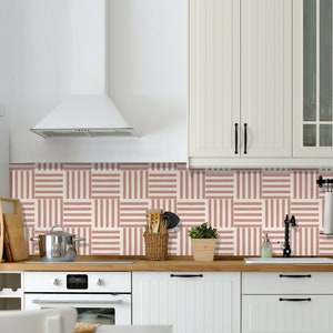 May include: A white kitchen with white cabinets and a white range hood. The backsplash is a pink and white striped tile pattern. There is a wooden countertop and a stainless steel sink.