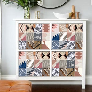 May include: White dresser with six drawers, each drawer front is covered with a removable patterned contact paper. The pattern is a patchwork of geometric shapes in shades of pink, brown, blue, and white.