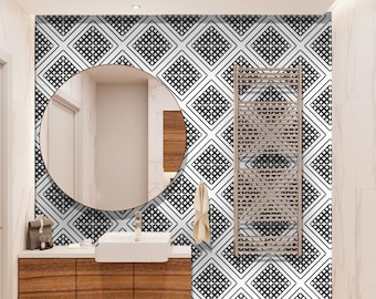 Puede incluir: Un baño moderno con una pared de azulejos con patrón geométrico blanco y negro, un espejo redondo, un tocador de madera con un lavabo blanco y un toallero.