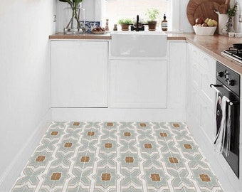 Può includere: Una piccola cucina con armadietti bianchi, un lavello in porcellana bianca e un bancone in legno. Il pavimento è piastrellato con un motivo geometrico in tonalità di blu e marrone.
