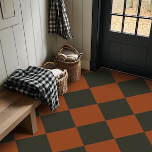 May include: A black and white checkered blanket draped over a wooden bench, with two woven wicker baskets containing soft textiles nearby. The floor features a large-scale terracotta orange and dark charcoal gray checkered tile pattern.