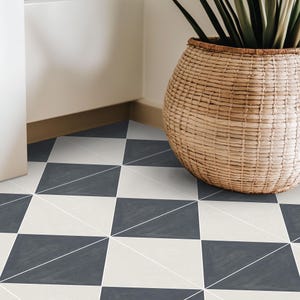 May include: A close-up of a floor with a geometric pattern. The floor tiles are arranged in a checkerboard design with alternating squares of dark grey and off-white. Thin white lines create triangles within the squares. A woven basket with a plant is in the corner.