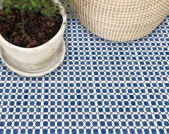Puede incluir: Un suelo blanco con un patrón geométrico azul y blanco. El patrón está formado por pequeños círculos y cuadrados. Un macetero blanco con una planta verde está en primer plano.