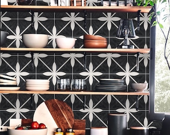 Puede incluir: Un interior de cocina con estantes de madera que exhiben varios platos, cuencos y objetos decorativos. El fondo presenta un diseño de azulejos florales en blanco y negro. Los estantes están soportados por soportes metálicos negros. Se ve una ventana con vistas a la vegetación.