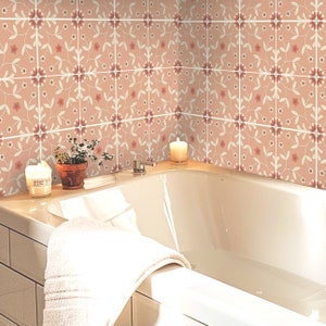 May include: A white bathtub with a pink floral tiled surround. The bathtub is partially filled with water and has a white towel draped over the edge. Two candles are on the edge of the tub.