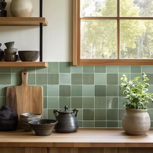 May include: A kitchen countertop with green tiled backsplash, a wooden chopping board, a ceramic teapot, and a potted plant. The countertop is made of wood and has a light brown finish.