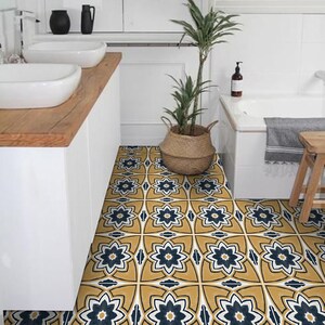 Könnte beinhalten: Ein Badezimmerboden mit gelben und blauen gemusterten Fliesen. Die Fliesen haben ein Blumenmuster. Der Boden befindet sich in einem Badezimmer mit einer weißen Badewanne und einer Arbeitsplatte aus Holz.
