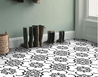 Puede incluir: Azulejos de suelo con estampado en blanco y negro con un diseño geométrico. Los azulejos están dispuestos en un patrón repetitivo. El suelo está en un pasillo con una pared verde y un par de botas de lluvia negras.