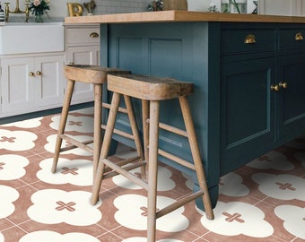 Può includere: Due sgabelli da bar in legno con un'isola da cucina verde acqua sullo sfondo. Il pavimento è piastrellato con un motivo geometrico bianco e rosa.