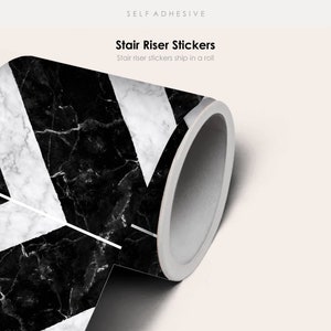 Könnte beinhalten: Eine Rolle selbstklebender Treppenstufenaufkleber mit einem schwarzen und weißen Marmormuster. Die Aufkleber sind in einem Chevron-Design. Der Text "Stair Riser Stickers" und "Stair riser stickers ship in a roll" ist auf dem Bild sichtbar.