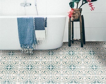 May include: A bathroom with a white bathtub and a plant in a brown pot on a wooden stand. The floor is tiled with a geometric pattern in shades of blue and beige.
