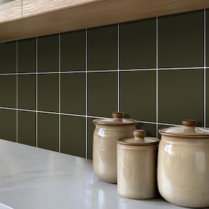 Puede incluir: Tres botes de cerámica con tapas marrones y un esmalte beige. Los botes están sobre una encimera blanca delante de una pared de azulejos cuadrados verde oscuro.