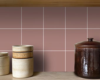 May include: A close-up of a kitchen backsplash with mauve square tiles. Three ceramic jars are on a wooden countertop in front of the tiles. A brown ceramic jar with a lid is on the right side of the image.