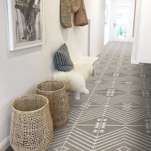 May include: A hallway with a white tiled floor featuring a geometric pattern in grey and white. The floor is tiled with square tiles. There is a white bench with a white faux fur throw and a grey patterned cushion. Two woven baskets are on the floor.