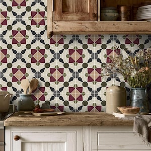 May include: A wall surface covered in square tiles featuring a repeating geometric pattern in shades of deep red, muted olive green, and beige. The design consists of stylized floral shapes and dark gray circular accents on a light cream background.