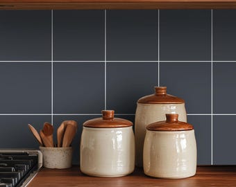 May include: Three ceramic kitchen canisters with glossy brown lids and speckled cream-colored bodies, accompanied by a small matching bowl containing several wooden spoons, arranged on a wooden countertop against a dark gray tiled backsplash.