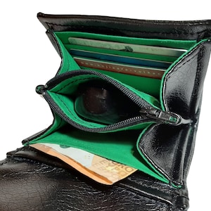 May include: Black leather wallet with a green lining and a zippered coin pocket. The wallet is open and has several cards and a bill inside.