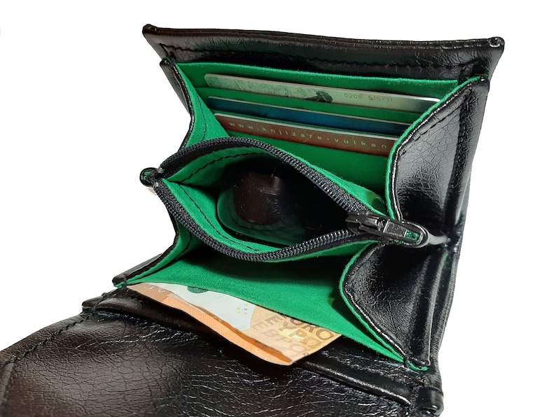 May include: Black leather wallet with a green lining and a zippered coin pocket. The wallet is open and has several cards and a bill inside.