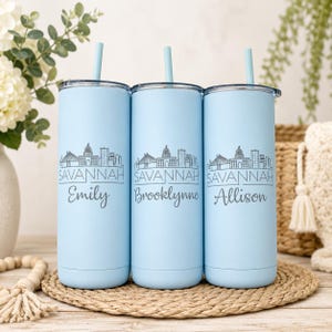 Pu&ograve; includere: Tre bicchieri cilindrici azzurri con cannucce abbinate, ognuno caratterizzato da un'illustrazione a linee grigio scuro dello skyline di Savannah, la parola SAVANNAH e un nome unico: Emily, Brooklynne o Allison in carattere corsivo.