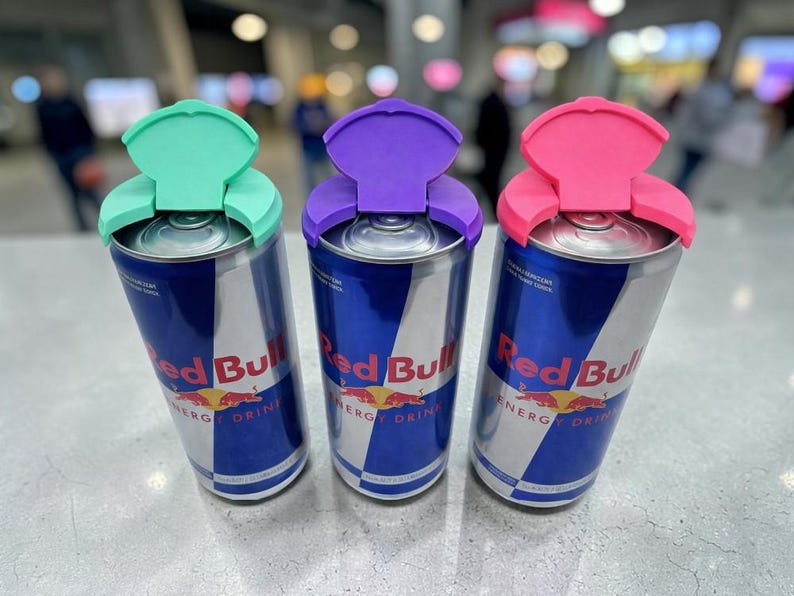 Puede incluir: Tres latas de bebida energ&eacute;tica Red Bull con tapas de colores verde menta, morado y rosa. Las latas tienen un dise&ntilde;o azul y plateado con el logotipo y el texto de Red Bull.