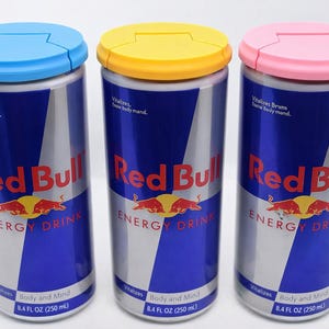 Puede incluir: Tres latas de bebida energ&eacute;tica Red Bull con tapas azules, amarillas y rosas. Cada lata tiene un dise&ntilde;o plateado y azul con el logotipo de Red Bull y el texto "ENERGY DRINK". Cada lata contiene 250 ml.