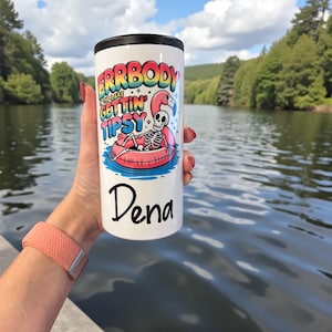 Könnte beinhalten: Ein weißer Becher mit schwarzem Rand. Er zeigt den Text "ERRBODY in the lake gettin' tipsy" und ein Skelett auf einem Flamingo-Schwimmer. Der Name "Dena" ist darunter in schwarzer Schrift gedruckt.