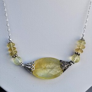 Puede incluir: Un collar de cadena de plata con un gran colgante de citrino amarillo y cuentas de citrino amarillo m&aacute;s peque&ntilde;as. El colgante est&aacute; engastado en un marco de filigrana de plata.