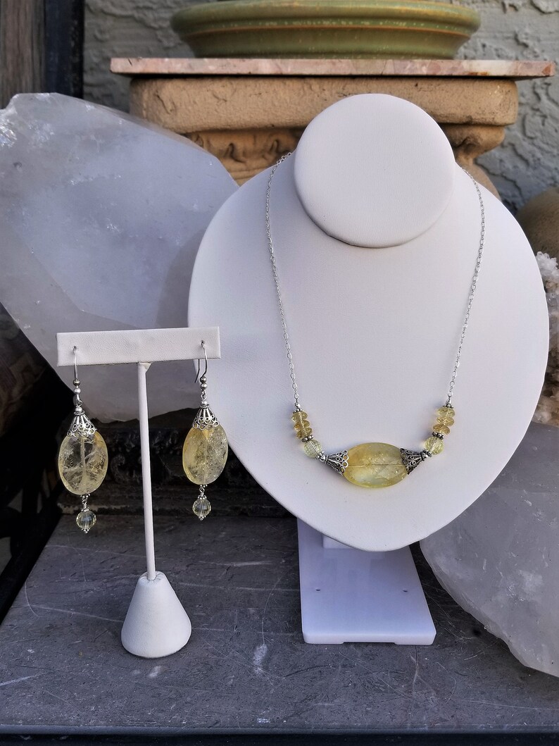 Puede incluir: Un conjunto de joyas de citrino amarillo que incluye un collar y pendientes. El collar tiene una cadena de plata con un gran colgante de citrino ovalado y cuentas de citrino m&aacute;s peque&ntilde;as. Los pendientes son de plata con una gran gota de citrino ovalado y una cuenta de citrine m&aacute;s peque&ntilde;a.