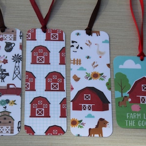 May include: Four rectangular bookmarks with farm-themed designs. One features a red barn on a blue background with the text "FARM LIFE IS THE GOOD LIFE." Other bookmarks have patterns of barns, trucks, and farm animals. Each has a ribbon.