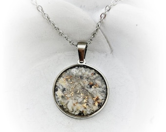 May include: A silver chain necklace with a round pendant. The pendant is filled with clear resin and contains small pieces of gold and white material, possibly pet fur.