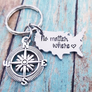 May include: Silver keychain with a compass charm and a US map charm with the text "No matter where" and a heart.