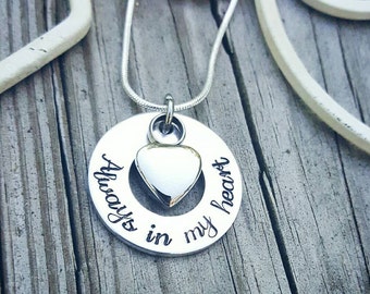 Op de afbeelding: Zilveren ketting met een ronde hanger met de tekst "Altijd in mijn hart" en een klein hartje.