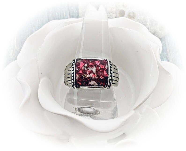 May include: A silver ring with a rectangular red and white stone inlay. The ring is set on a white background.