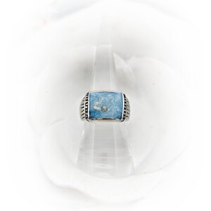 May include: A silver ring with a square blue stone set in the center. The stone has a white swirl pattern.