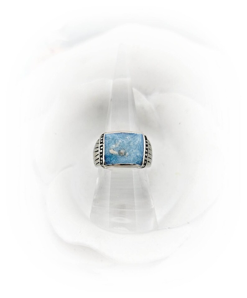 May include: A silver ring with a square blue stone set in the center. The stone has a white swirl pattern.