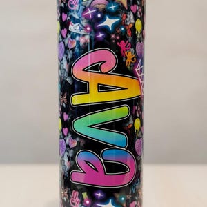 May include: A cylindrical tumbler with a black lid featuring a black marble-like background covered in colorful icons including hearts, stars, sneakers, and monkeys. The word "GAVA" is printed vertically in large, gradient rainbow-colored letters.